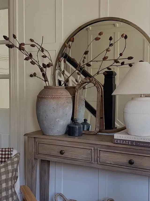 entryway table decor with rustic vase branches mirror lamp and stacked books