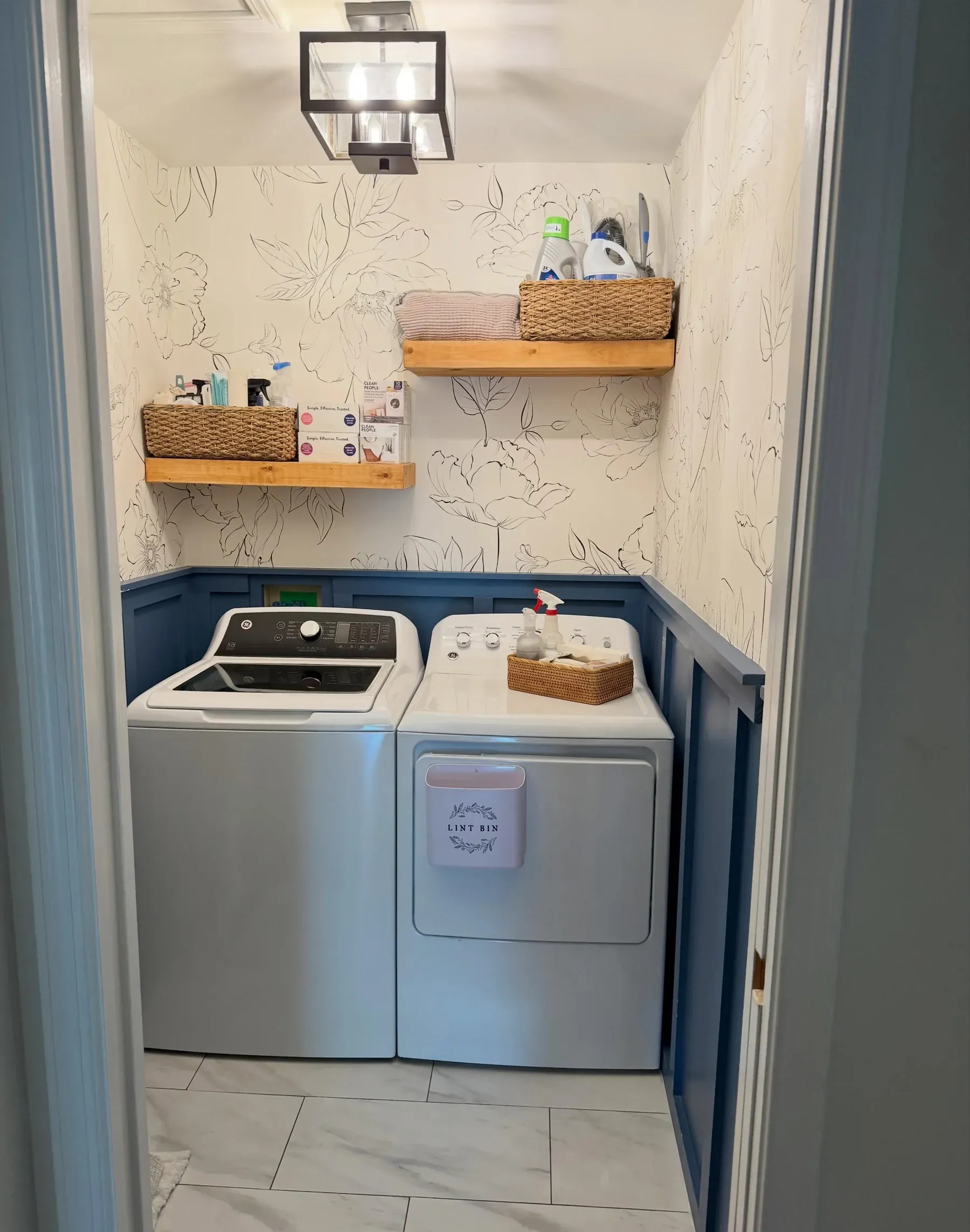 small laundry room ideas with top load washer dryer, wood shelves, baskets, laundry supplies, and blue trim