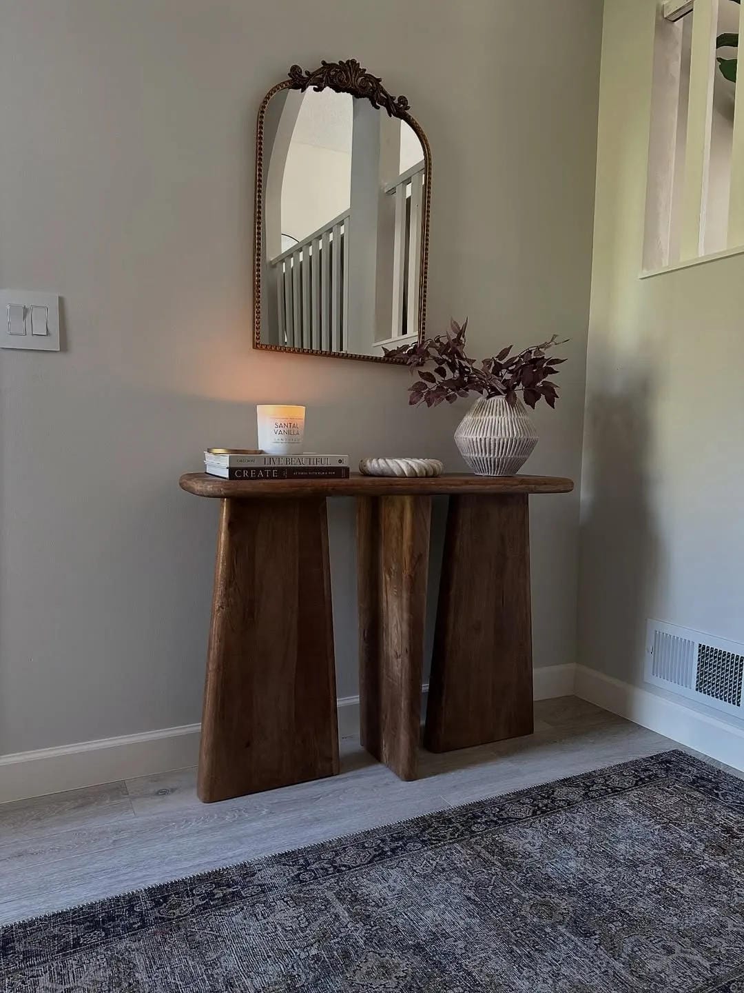 fall entryway table decor ideas with wood console, arched mirror, candle, bowl, and burgundy stems