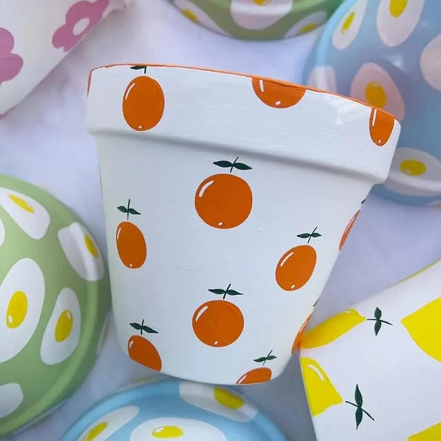 painted flower pot idea with white base and orange fruit pattern