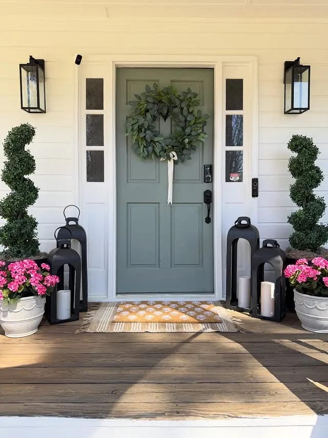 front porch planter inspiration with spiral topiaries black lanterns and pink flowers