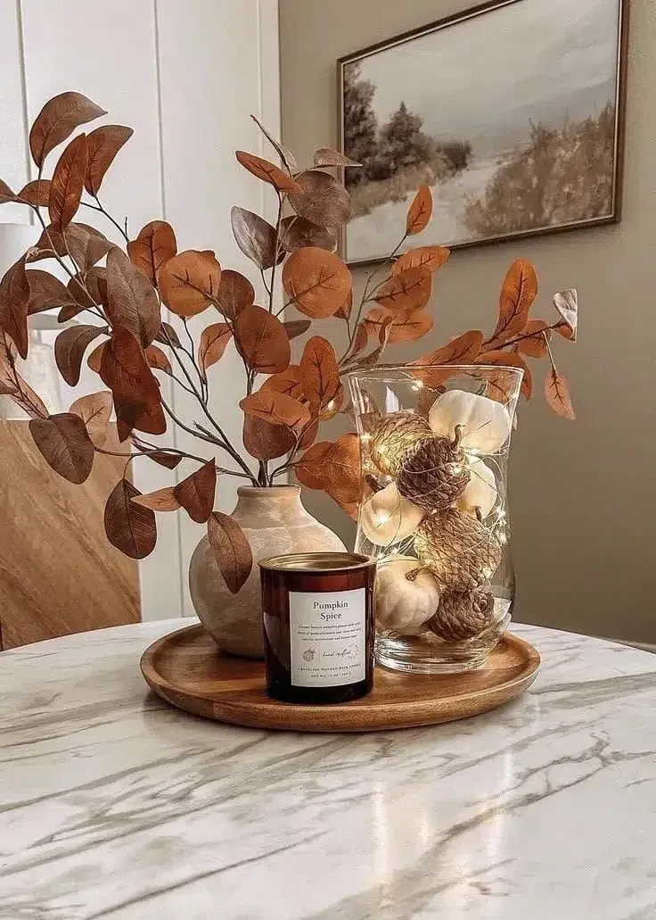 fall table decor ideas with small tray, candle, dried flowers, vase, glass hurricane, and simple autumn styling