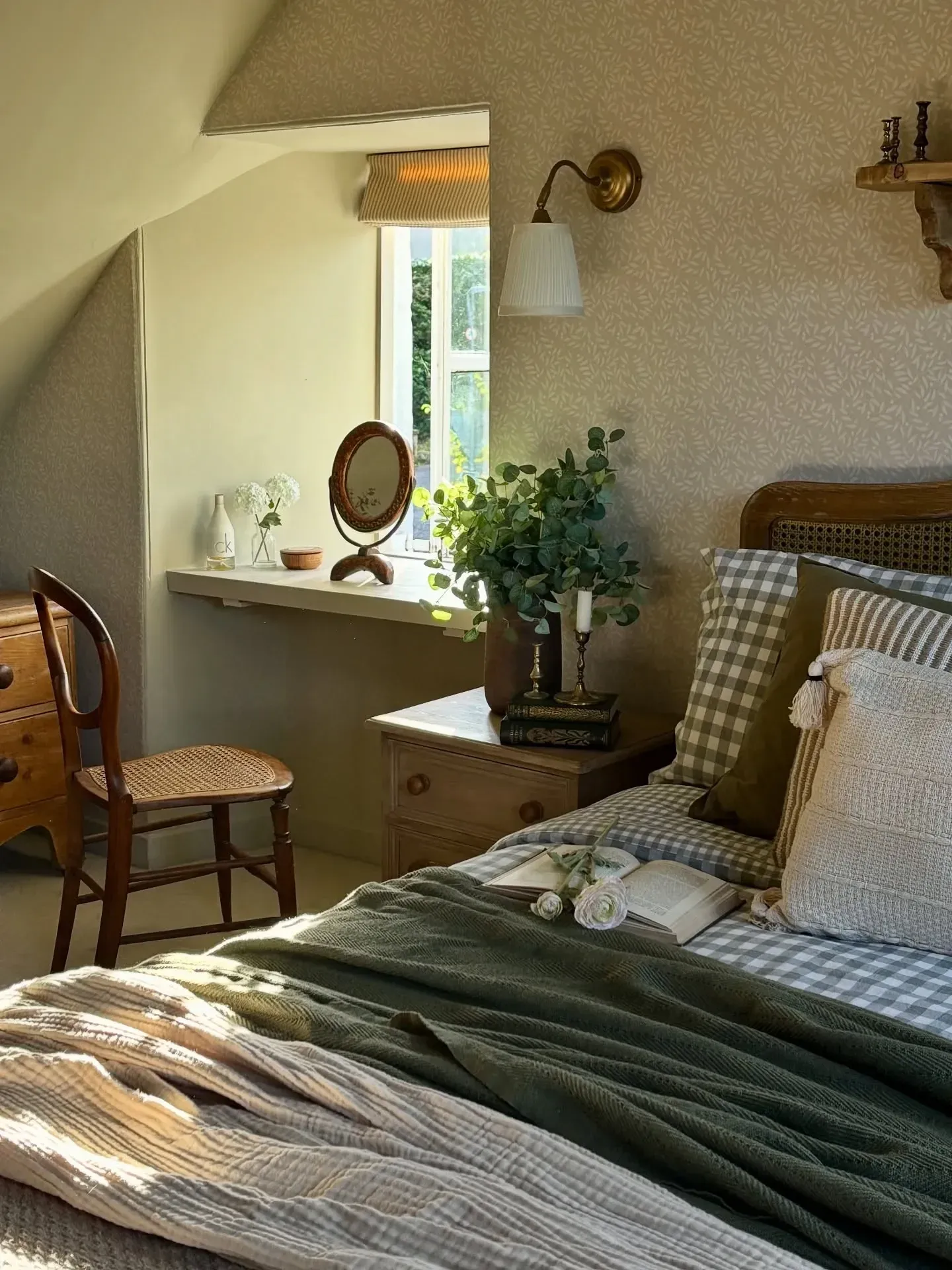 vintage home decor ideas for bedroom with small desk, cane chair, vintage mirror, wall sconce, and green bedding