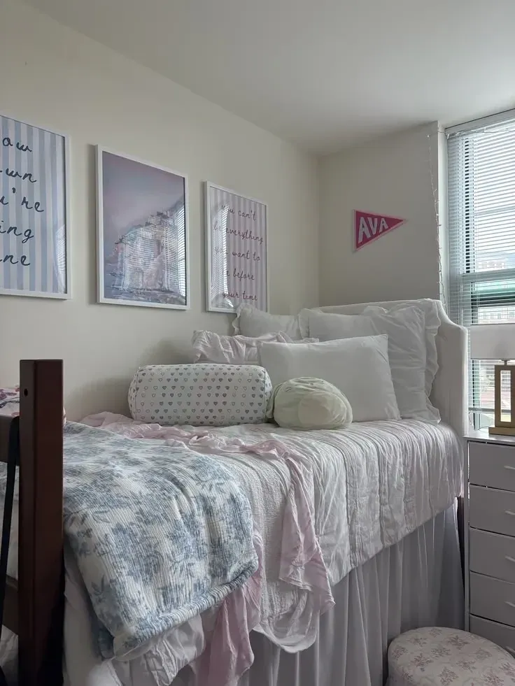 pink and blue dorm room ideas with pastel bedding, pale blue throw, pink blanket, simple wall art, and dorm bed