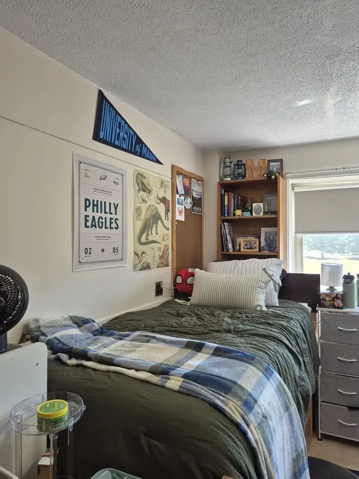 dorm decorating ideas for guys with sports posters, pennant, blue and green bedding, shelf decor, and dorm bed