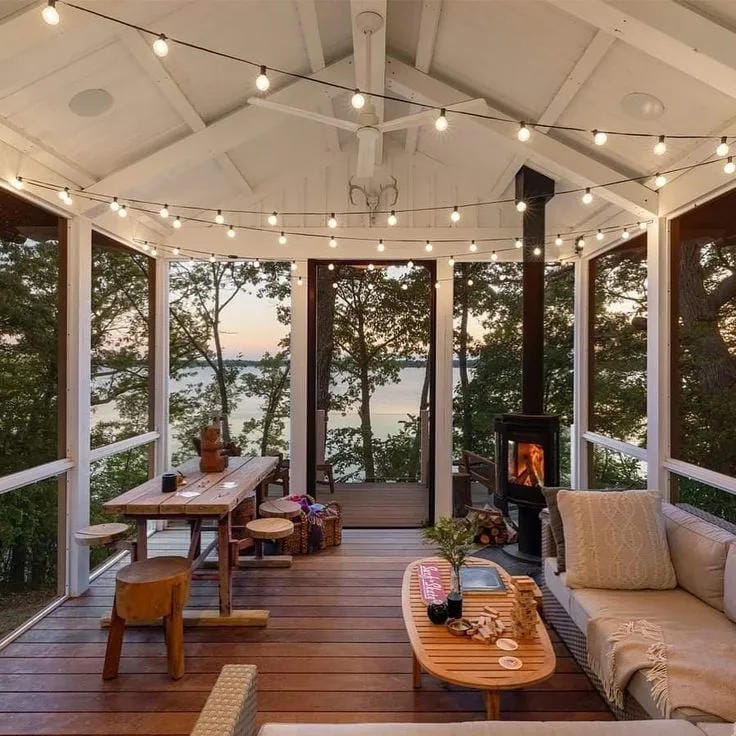 screened in porch decorating ideas with string lights wood stove sofa and lake view