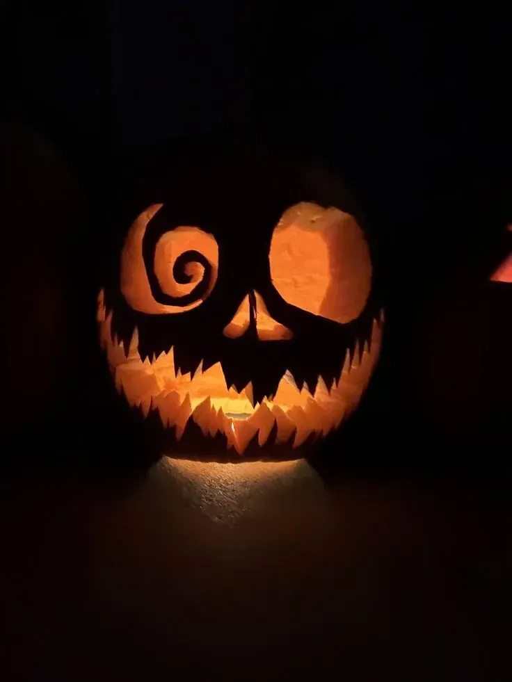 kid friendly pumpkin carving ideas with swirly monster eye, glowing round eye, and jagged smile