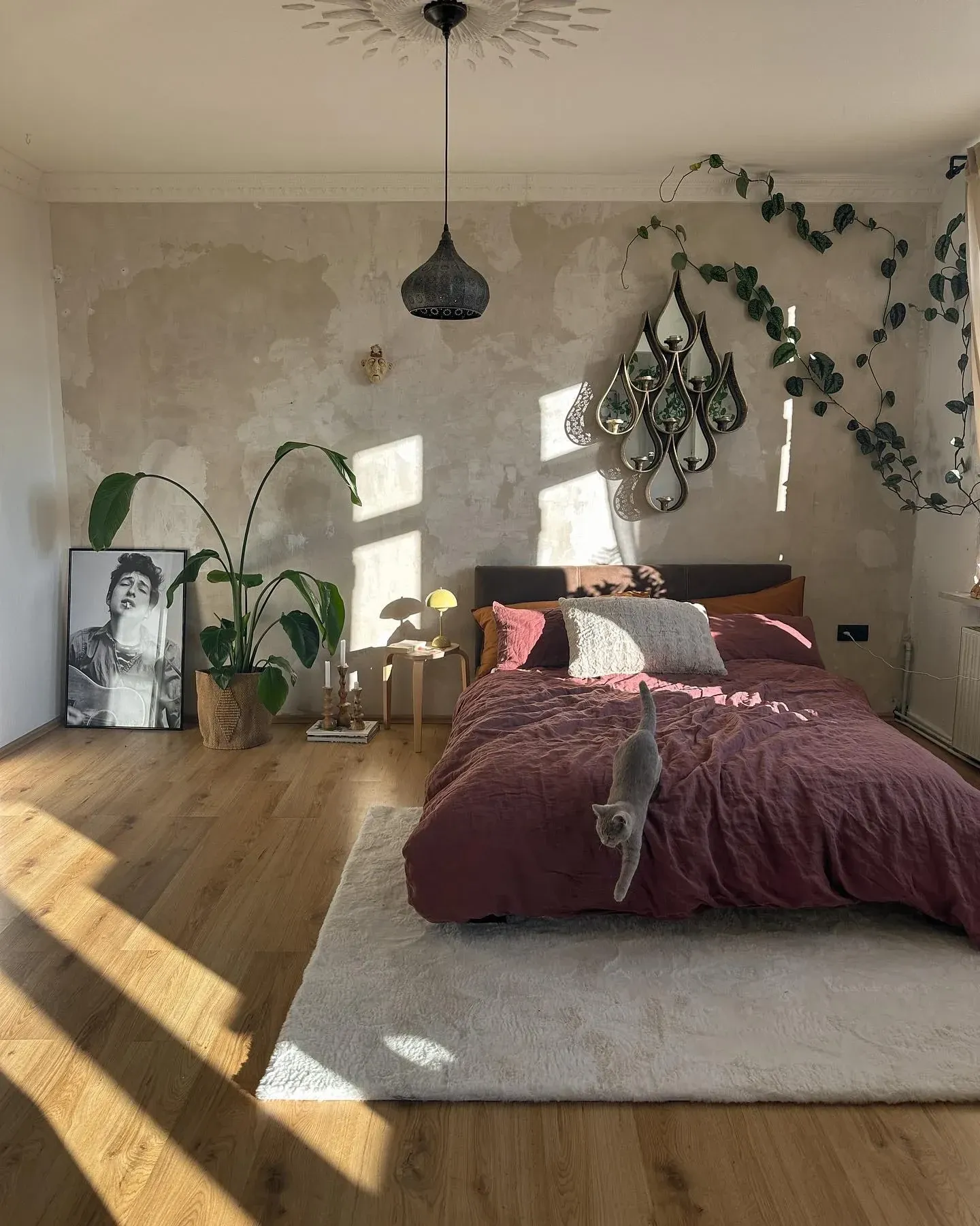dark boho bedroom ideas with textured wall, plants, burgundy bedding, hanging decor, and soft rug