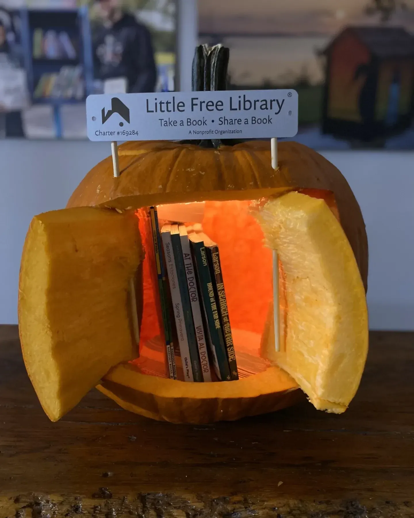 kid friendly pumpkin carving ideas with little free library pumpkin, carved door, books inside, and tiny sign