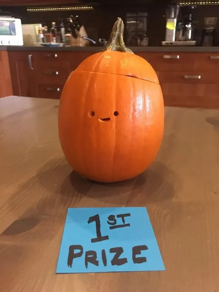kid friendly pumpkin carving ideas with tiny simple face, small eyes, and little smile on orange pumpkin