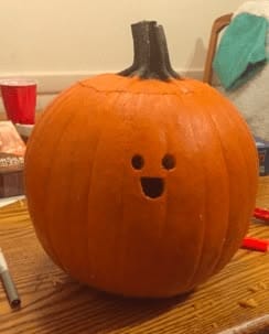 kid friendly pumpkin carving ideas with tiny ghost face, small eyes, and simple mouth cutout