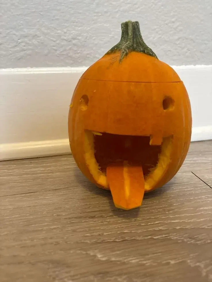 kid friendly pumpkin carving ideas with funny small pumpkin face, round eyes, open mouth, and tongue