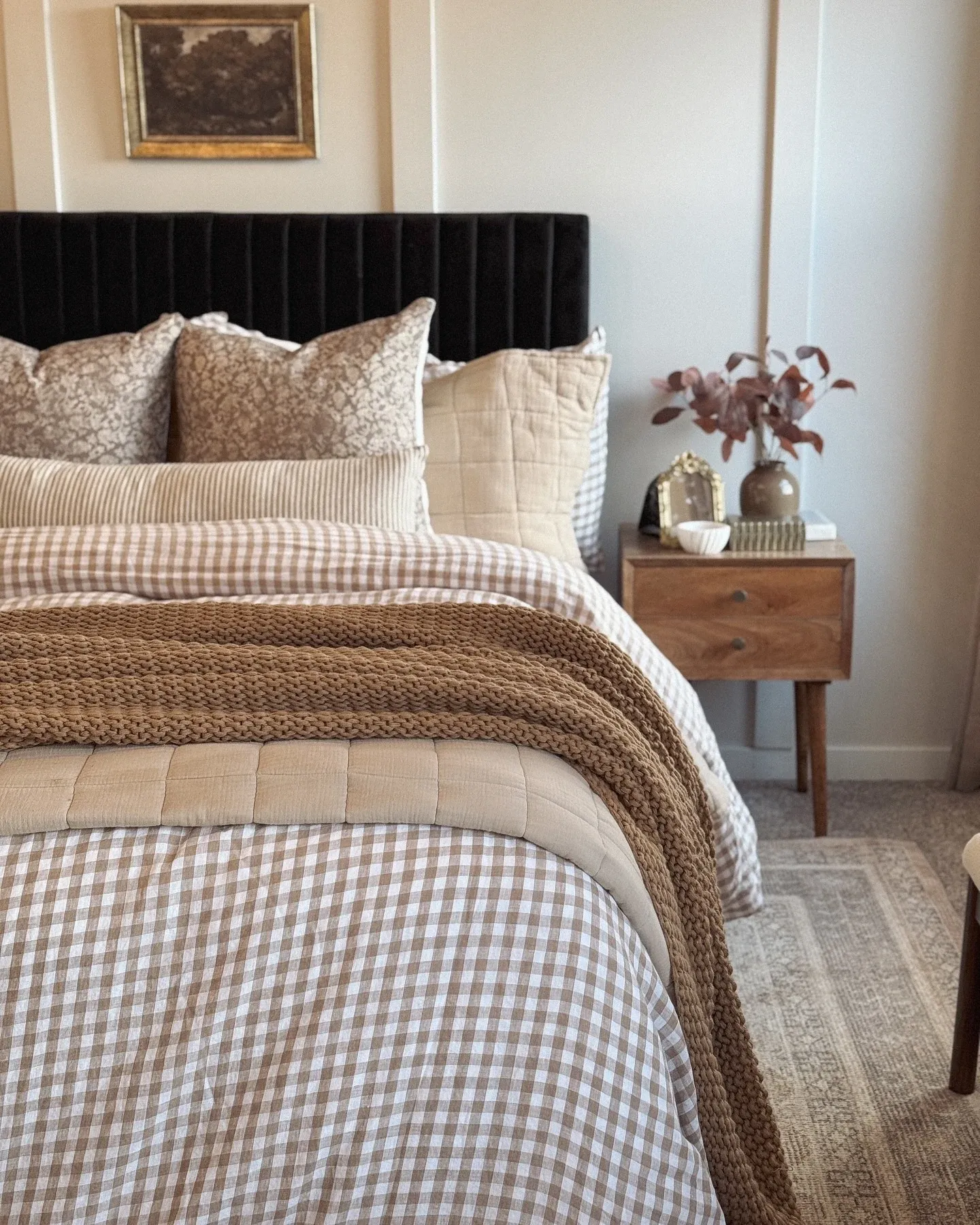 fall bedroom ideas with gingham duvet cover, chunky knit blanket, warm pillows, wood nightstand, and small vase