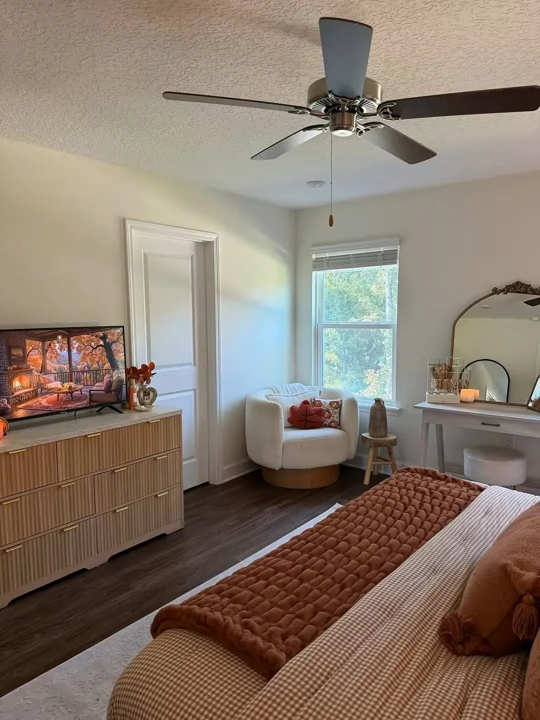 fall bedroom ideas with orange and white theme, rust blanket, white bedding, small pumpkin, wood dresser, and bright fall bedroom decor