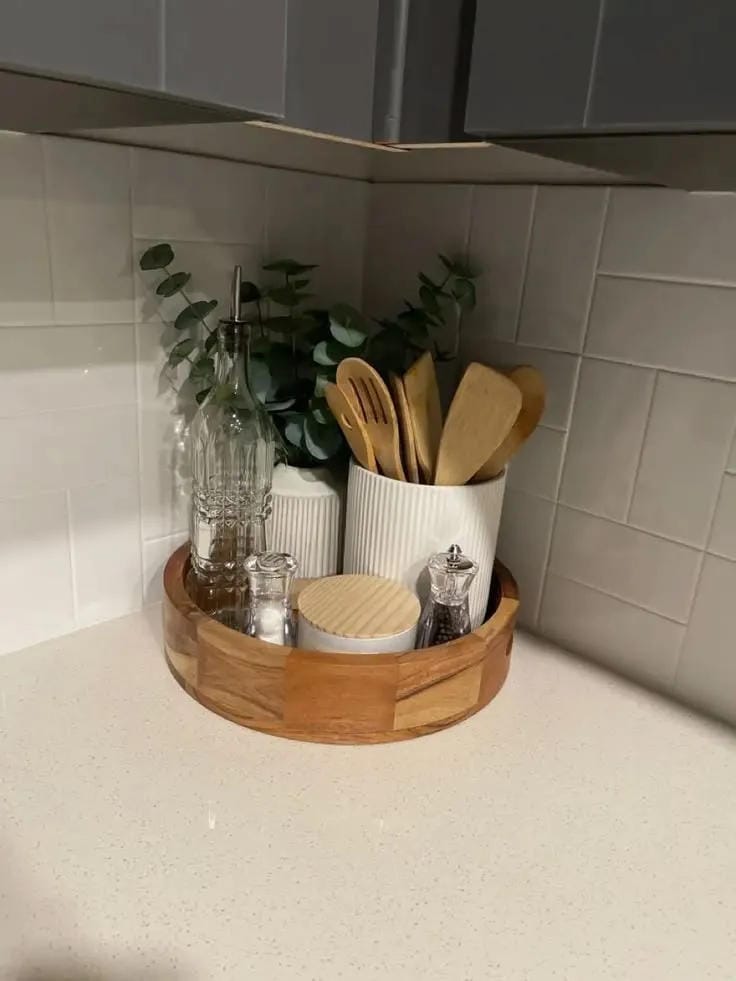 kitchen counter organization ideas with round wood tray utensils vase and greenery
