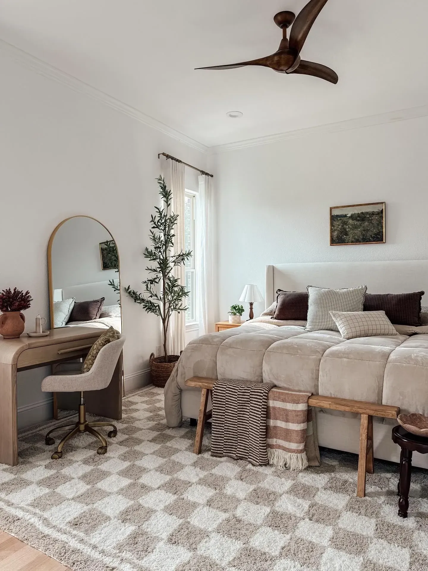 dark boho bedroom ideas with vanity corner, mirror, small desk, bench, soft bedding, and tall plant