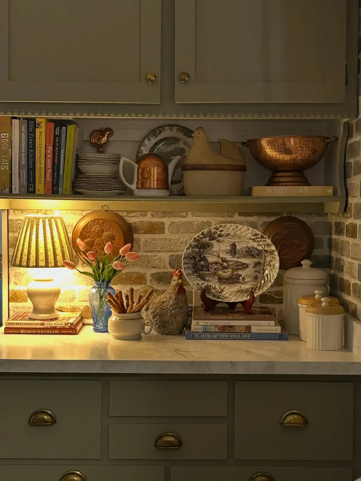 vintage home decor ideas with lit kitchen shelf, transferware plate, cookbooks, copper bowl, lamp, and collected dishes