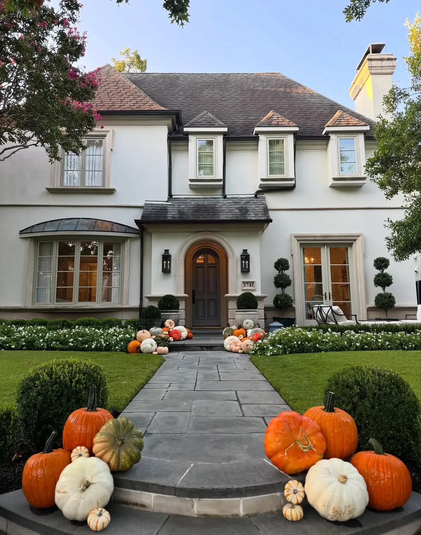 fall porch decor ideas with pumpkins lining a front walkway, white pumpkins, orange pumpkins, green pumpkins, and a classic front entry