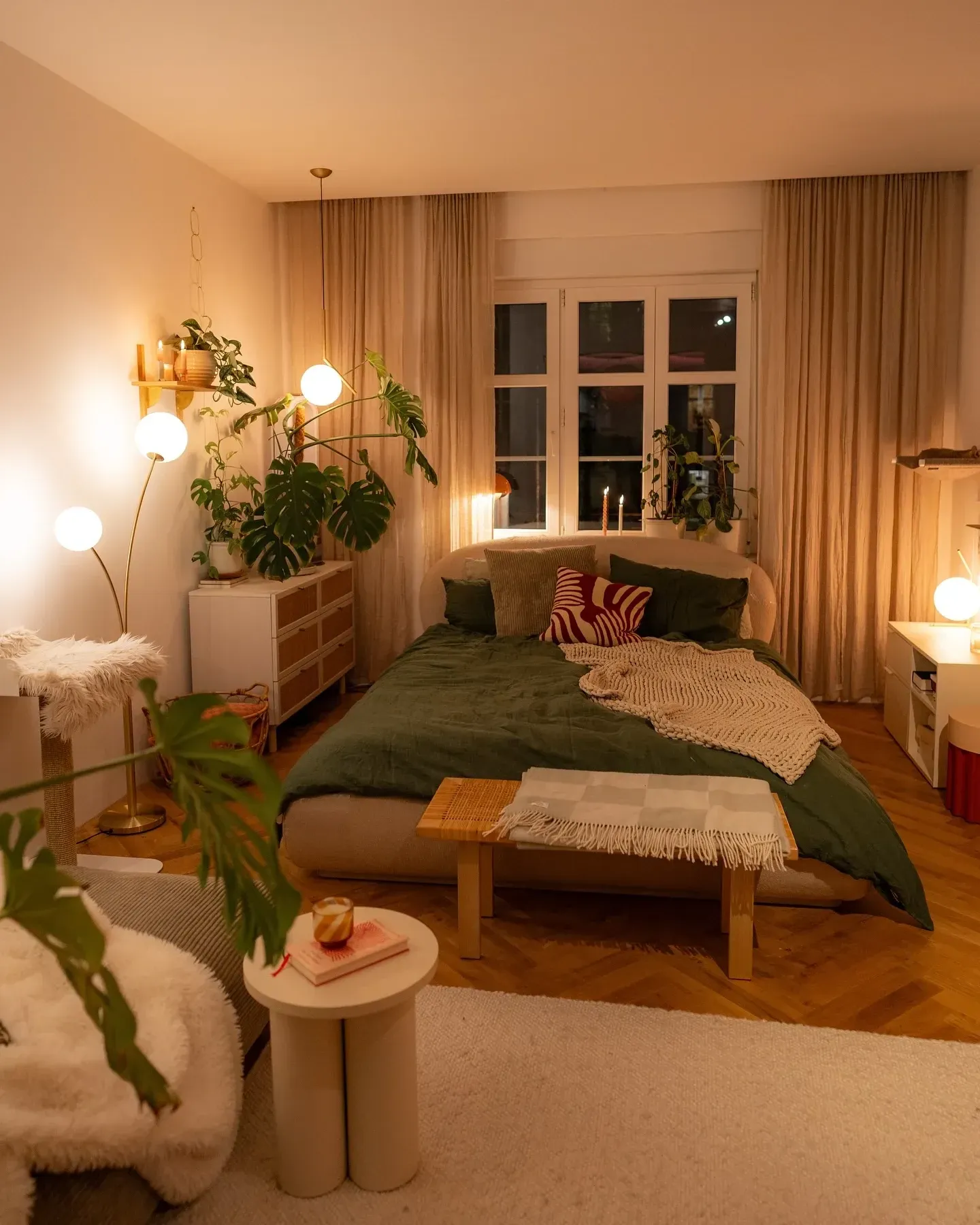 dark boho bedroom ideas with warm lamps, green bedding, plants, curtains, and cozy bedroom decor