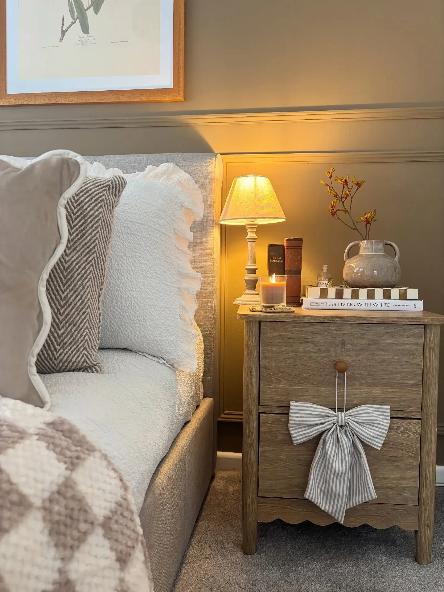 fall bedroom ideas with warm bedside lamp, layered pillows, floral bedding, tray, wood nightstand, and fall stems