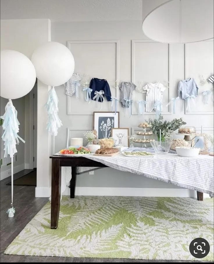 simple boy baby shower decor with white balloons and baby clothes