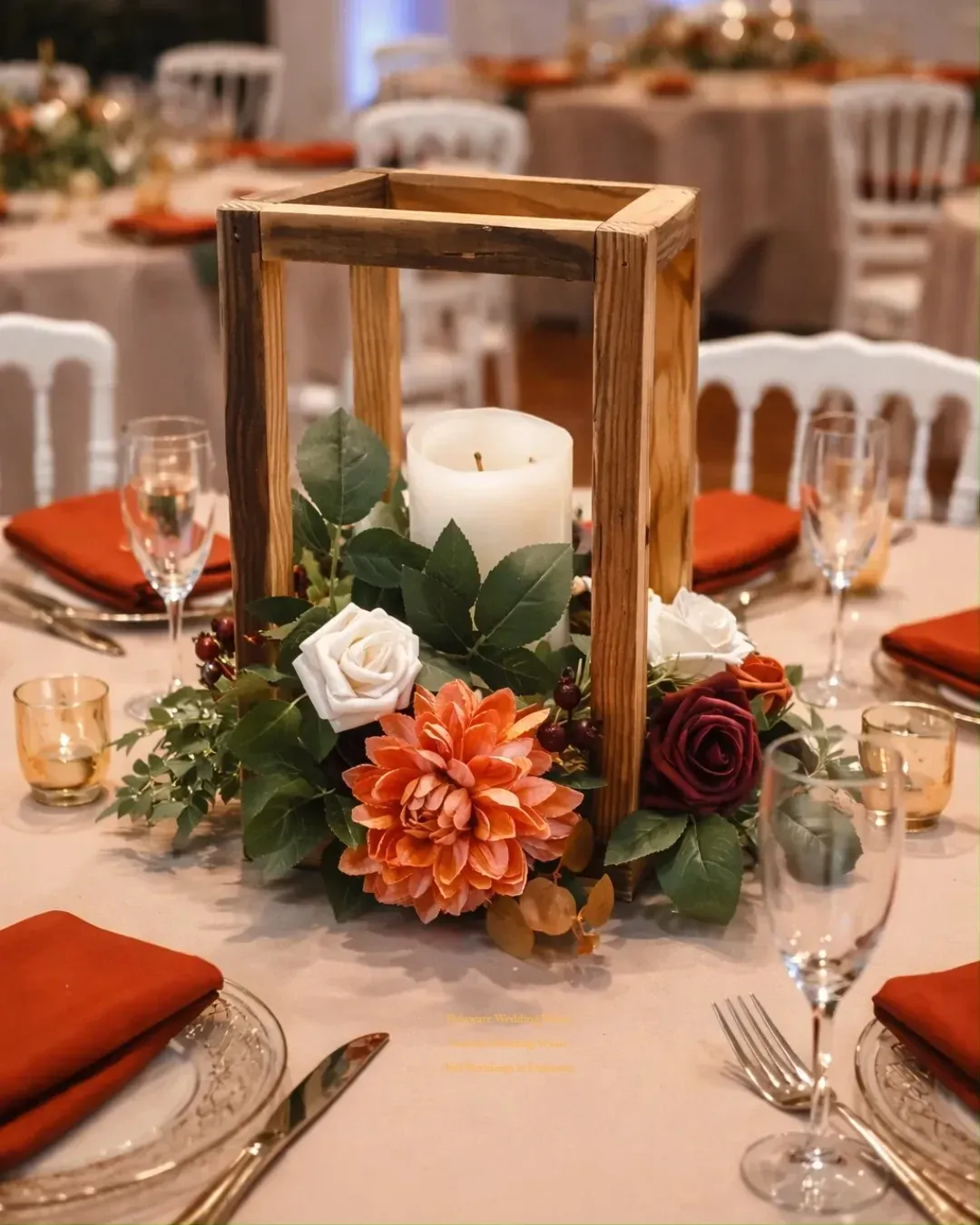 fall table decor ideas with wooden lantern centerpiece, candle, greenery, roses, orange flower, and warm napkins