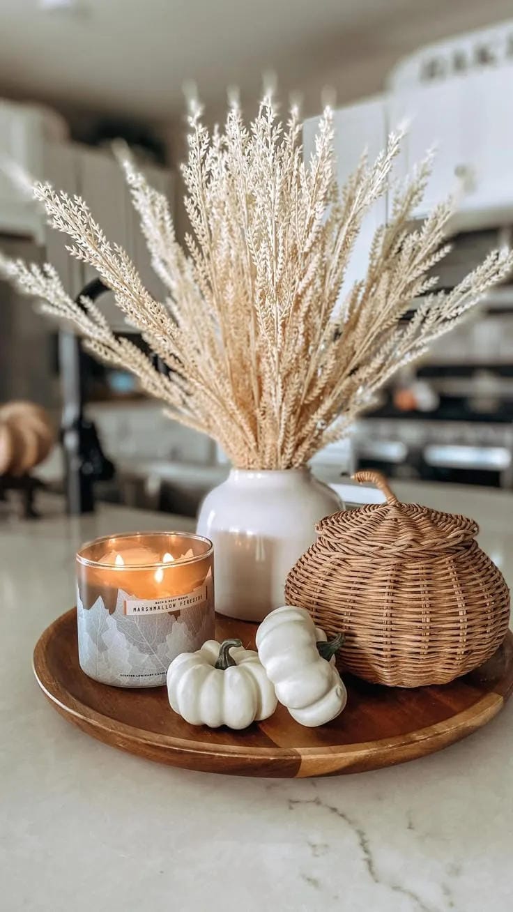 fall entryway table decor ideas with pampas grass in white vase, wicker pumpkin, white pumpkins, candle, and wooden tray