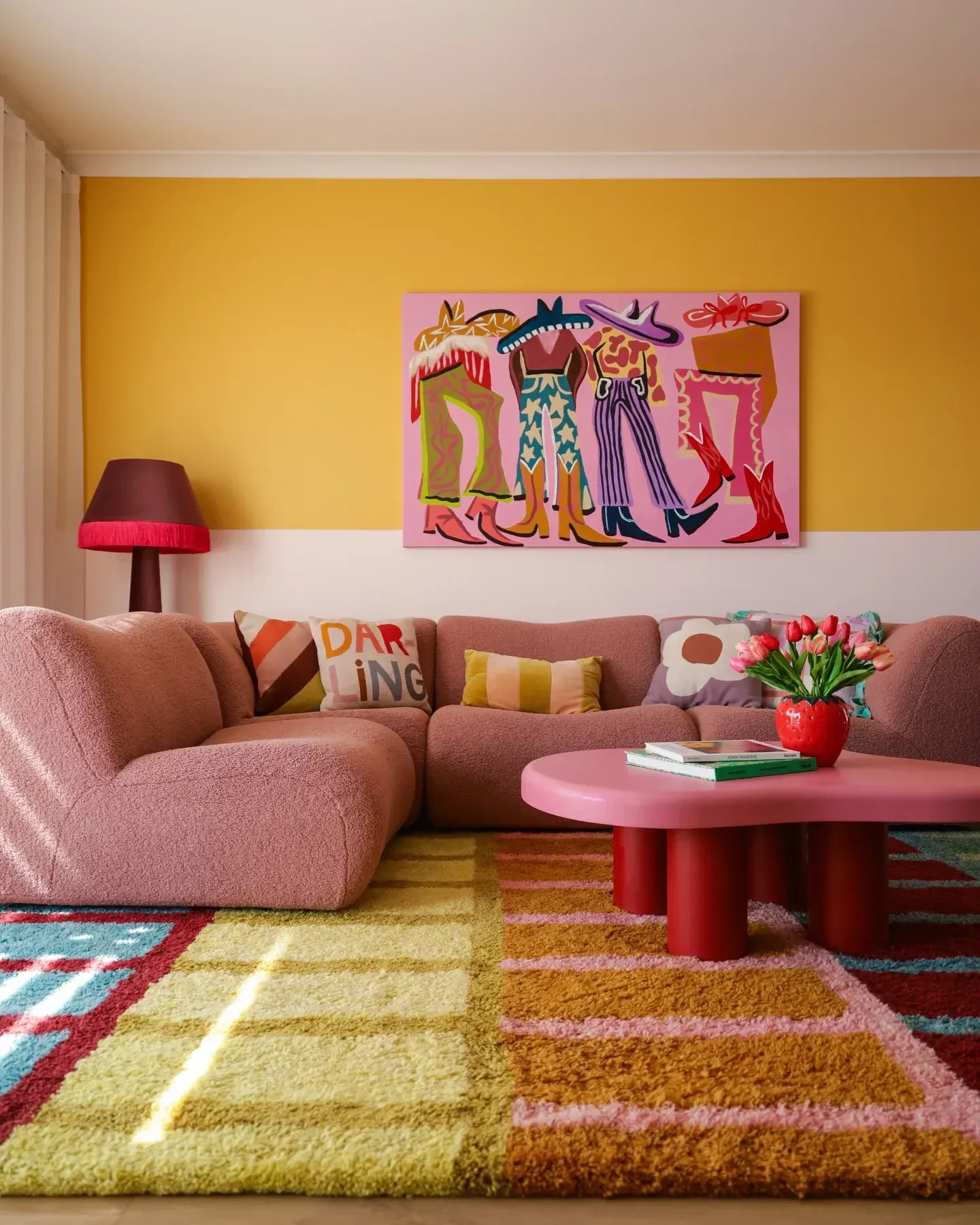 colorful living room ideas with yellow walls, pink sofa, red coffee table, colorful art, and patterned rug